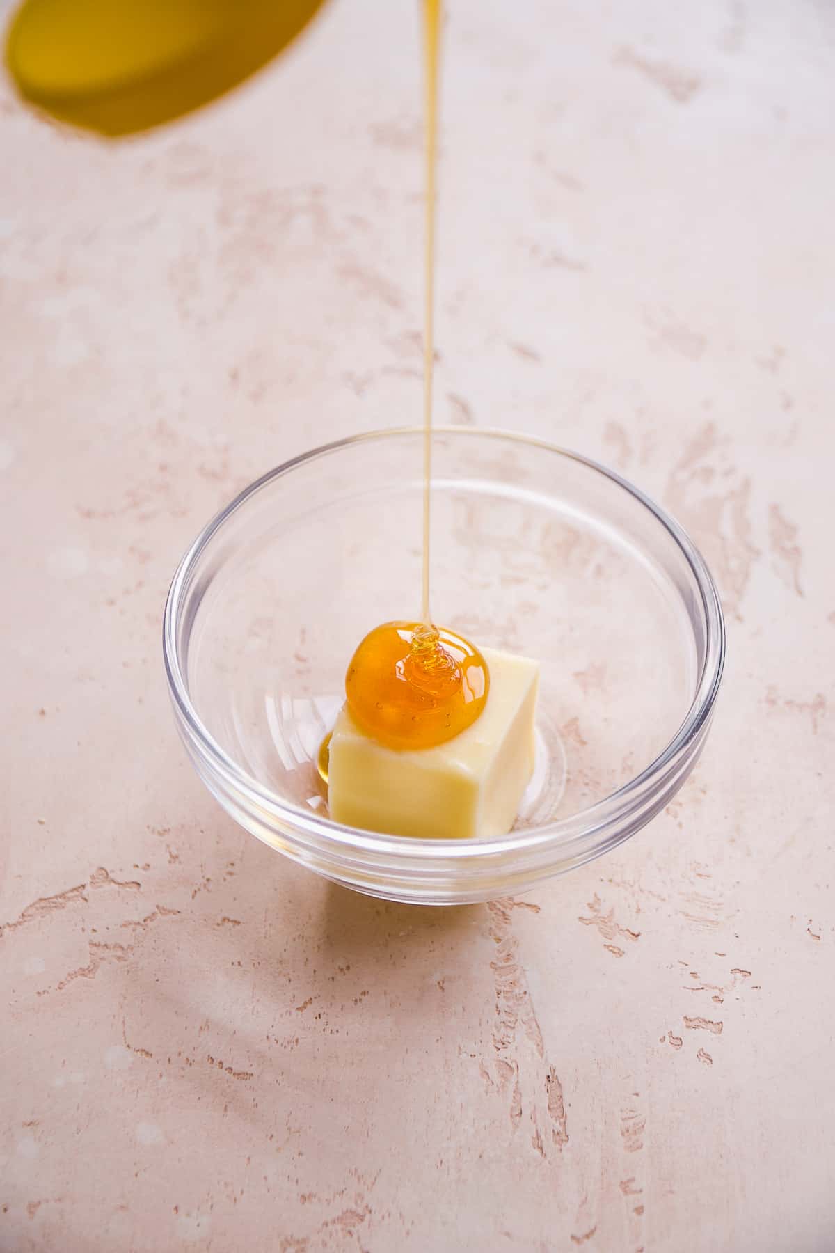 Honey being poured into a bowl with butter.