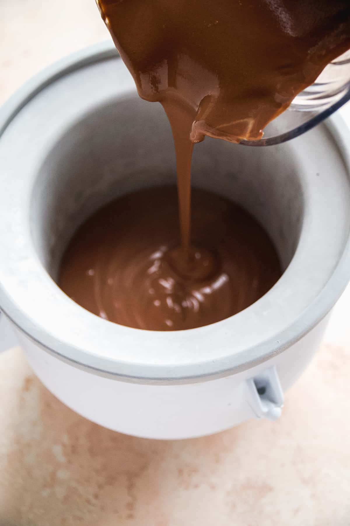 Chocolate yogurt mixture being poured into an ice cream maker.