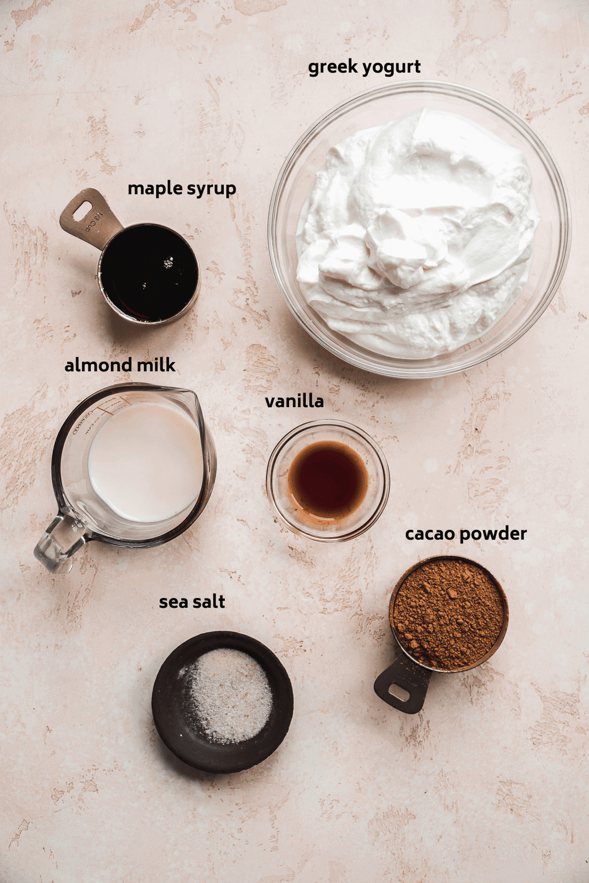 Chocolate frozen greek yogurt ingredients scattered on a pink surface.