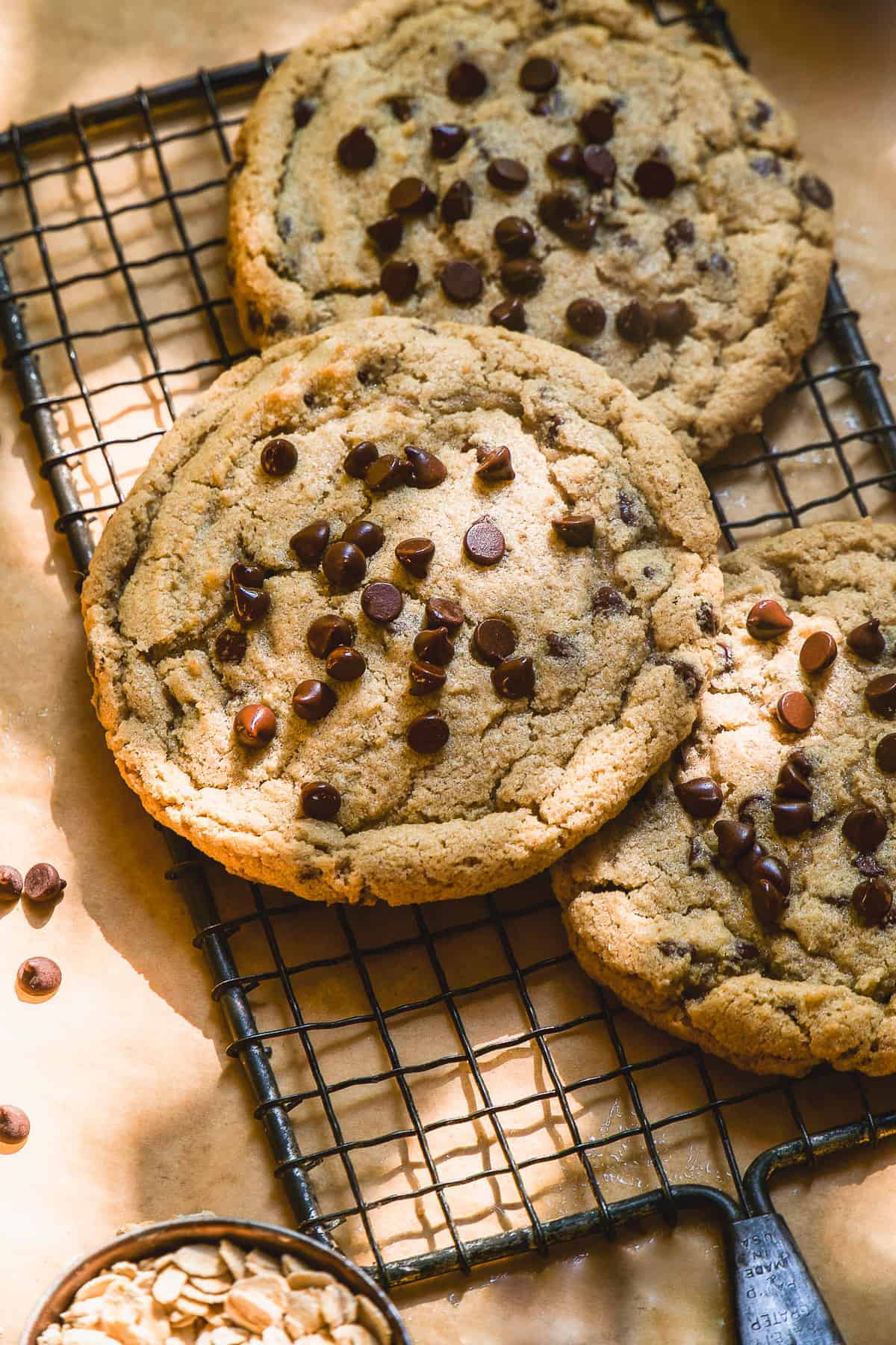 Oatmeal chocolate chip cookie spread out on a cooling rack.