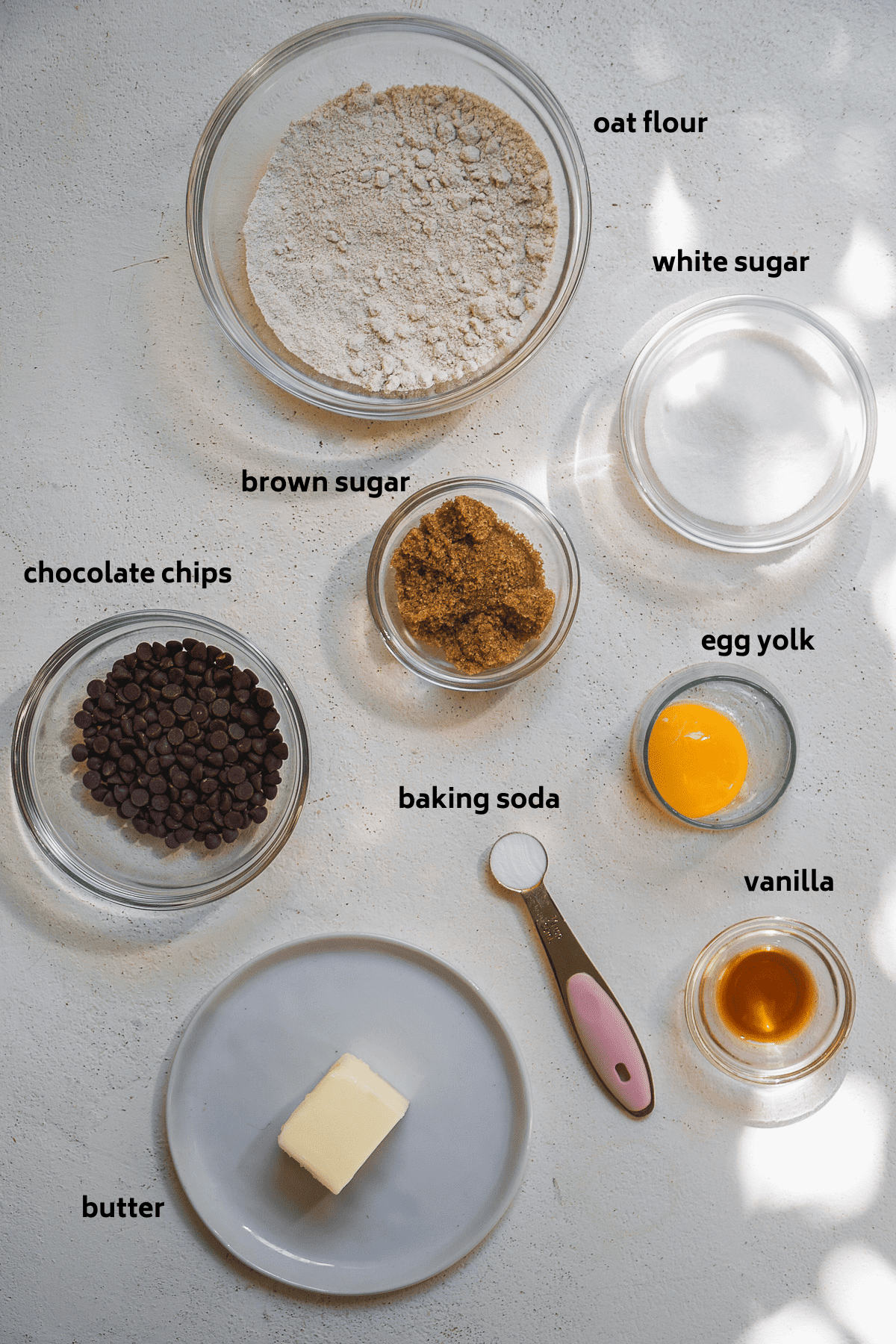 Oatmeal cookie ingredients on a white surface with labels in black.