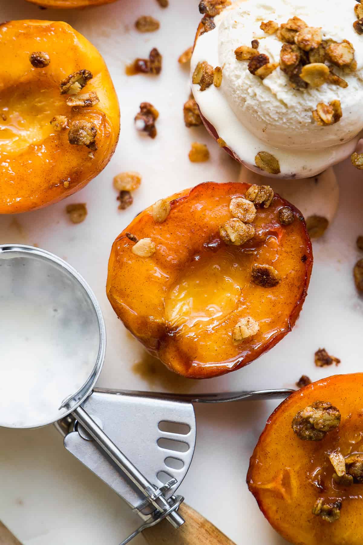 Overhead view of roasted peaches with oat crumble and ice cream.