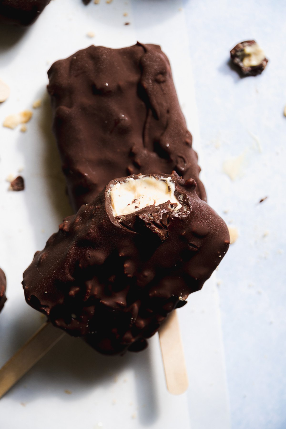 Frozen yogurt bars covered in chocolate with a bite taken out of one.
