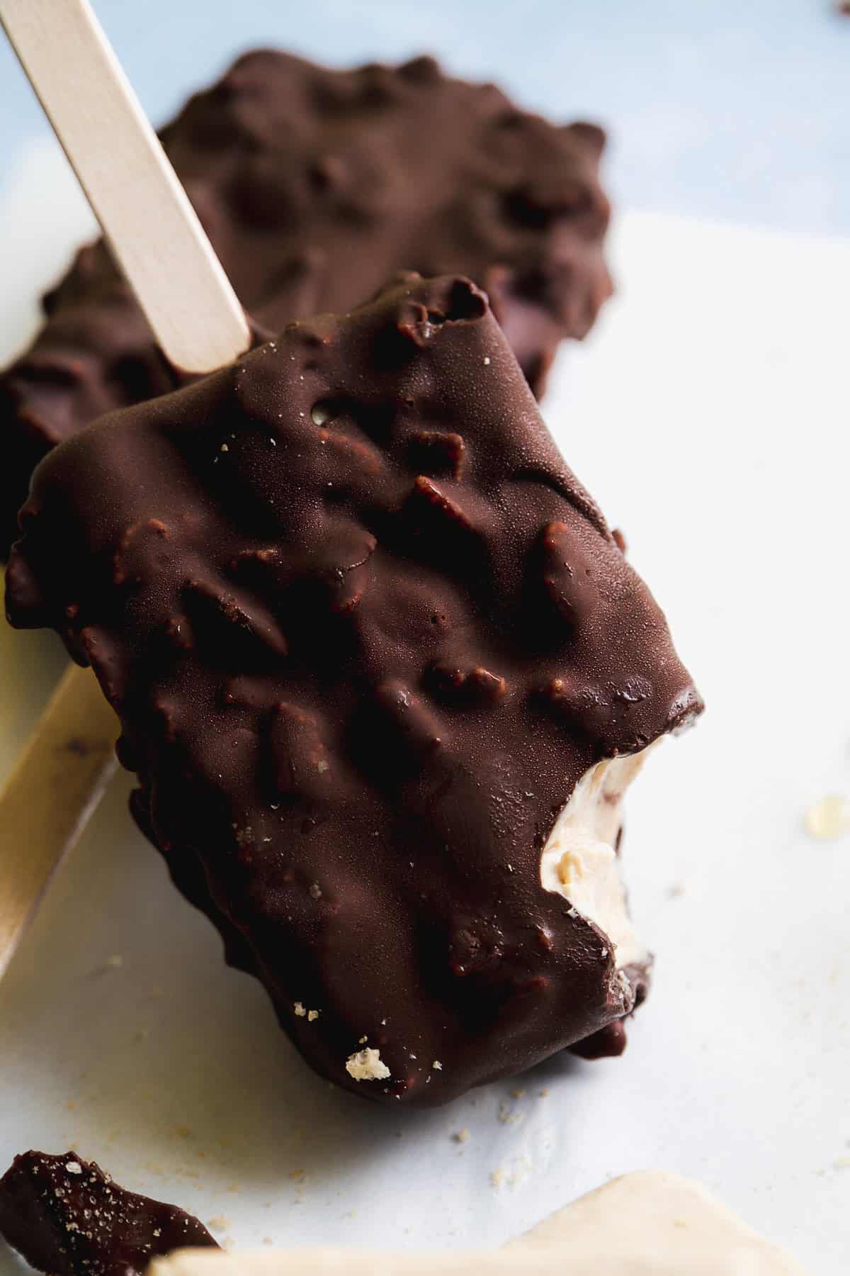 Frozen chocolate yogurt bar with a bite taken out of it.