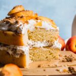 Peach cobbler layer cake with a pile of cool whip and peach slices on top.