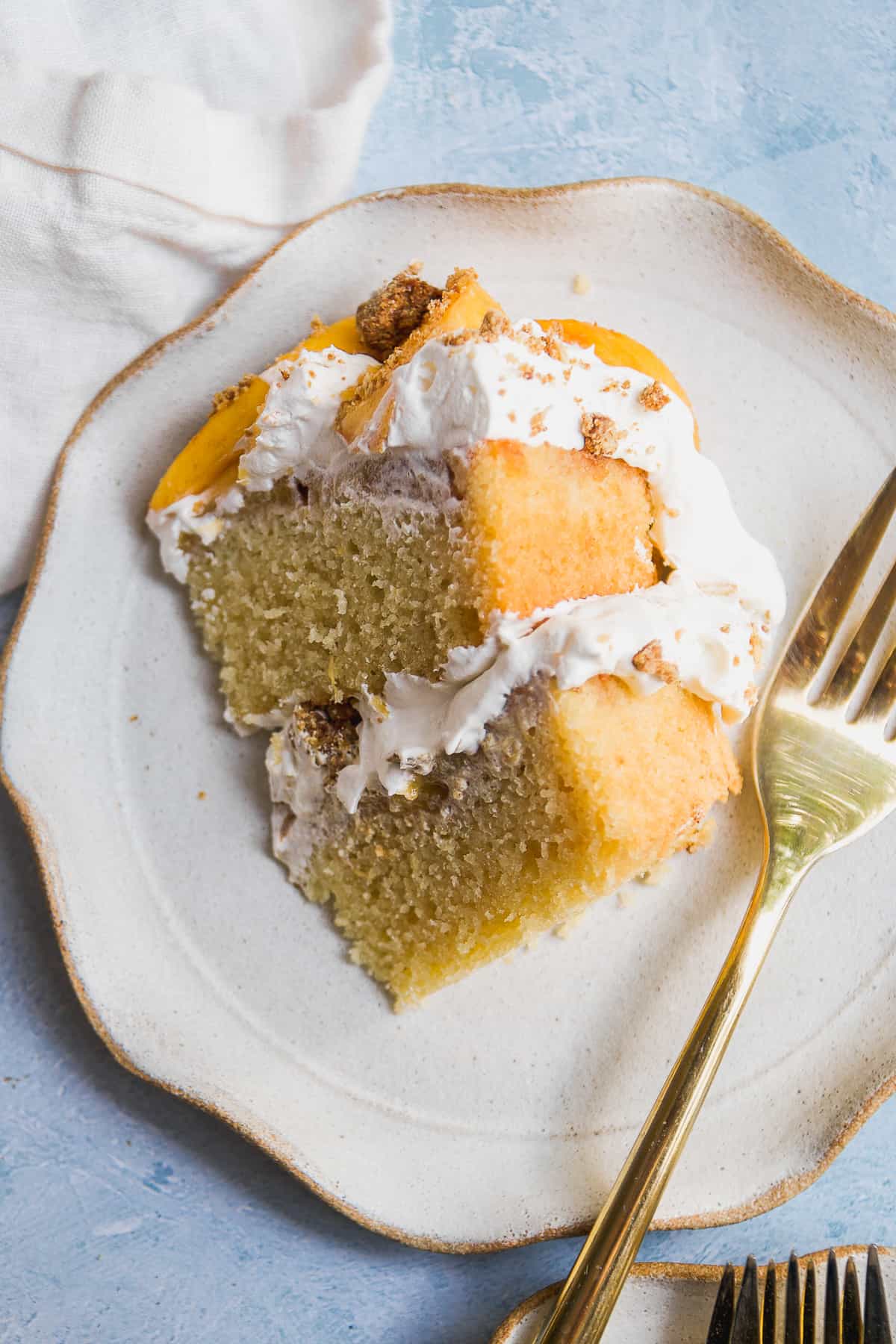 A slice of peach cobbler pound cake on a plate with a gold fork.