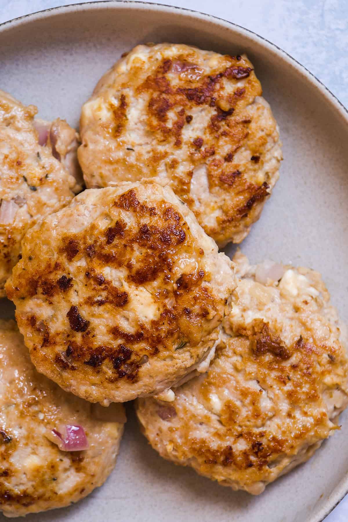 Cooked juicy chicken burgers on a plate.