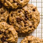 Vegan peanut butter chocolate chip cookies scattered on a wire rack.