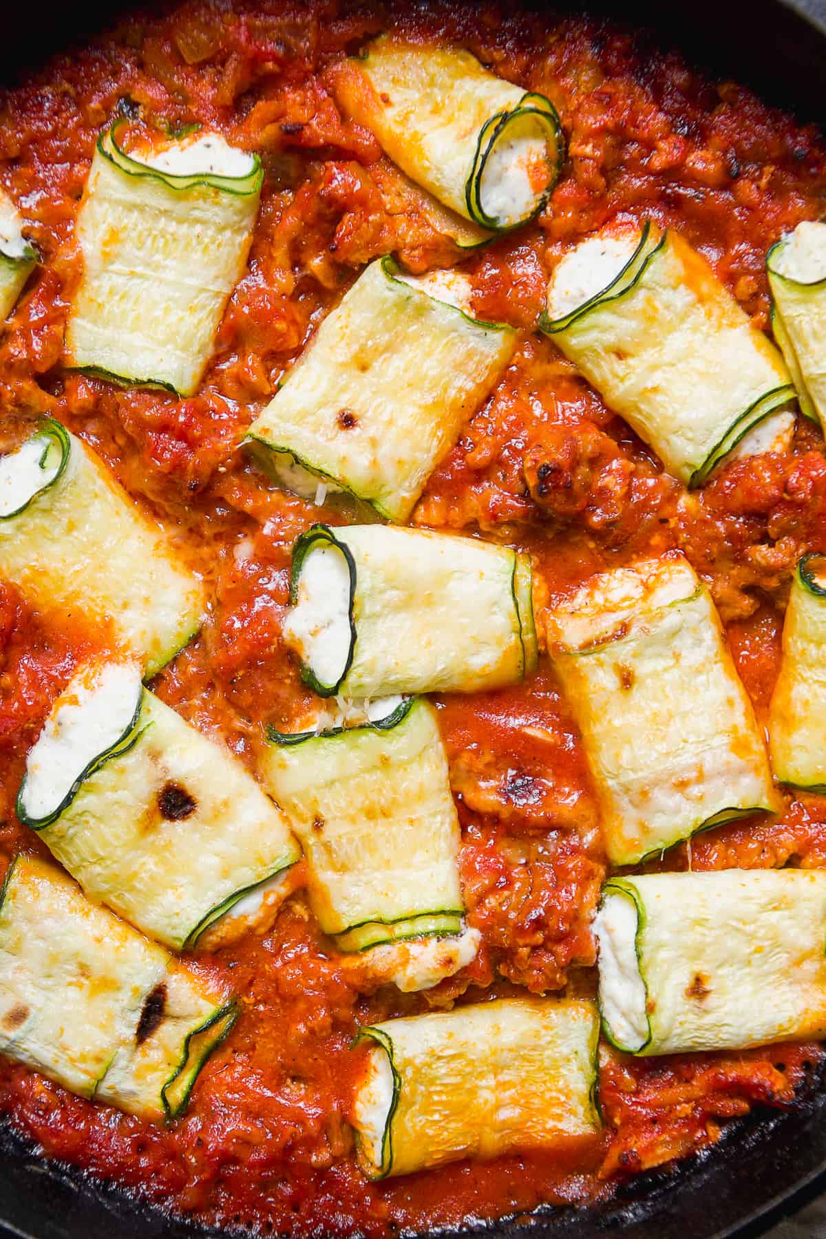 Overhead view of zucchini roll ups baked in tomato sauce.