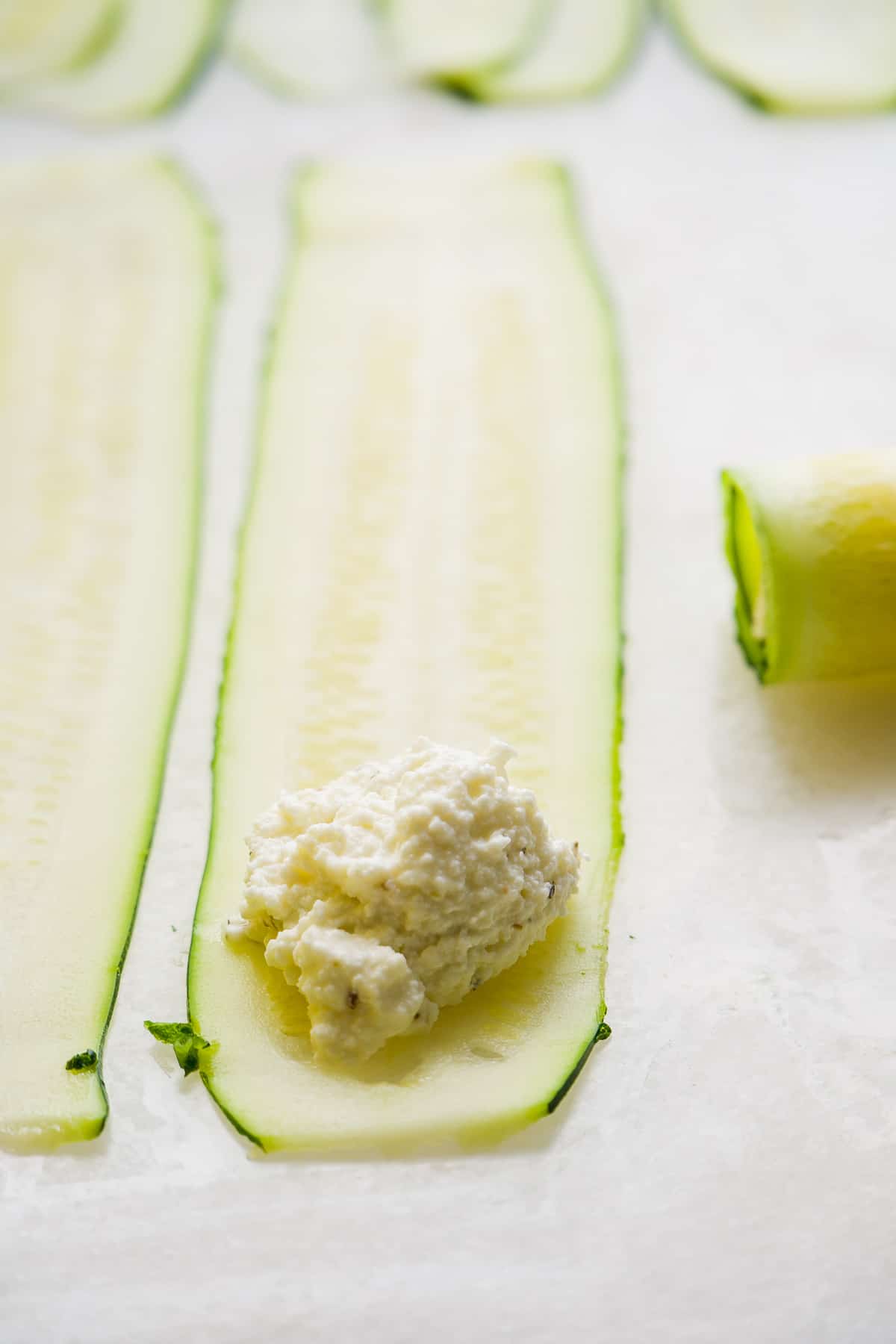 Ricotta cheese on the edge of a thin slice of zucchini.