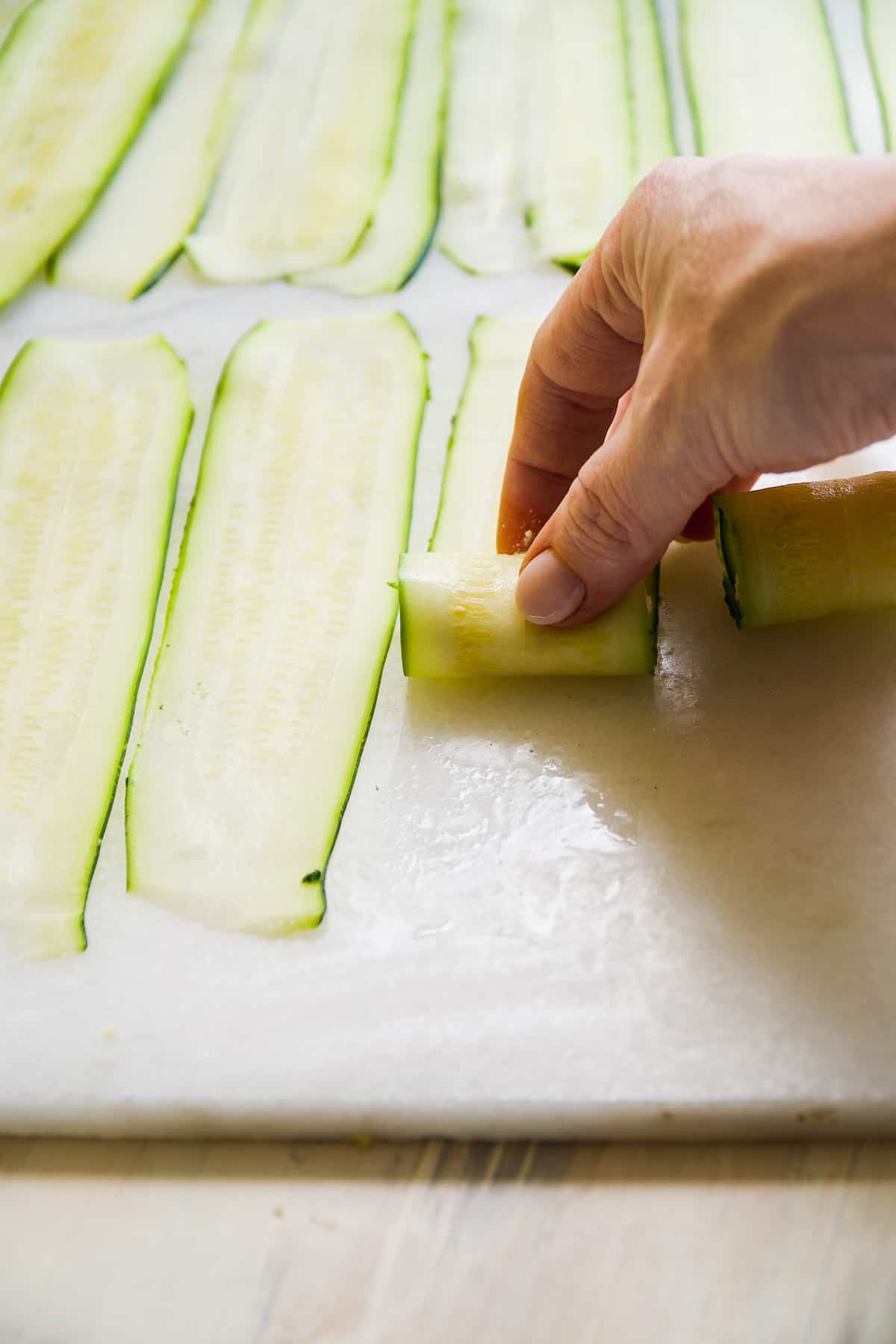 Zucchini slice being rolled up with ricotta inside.