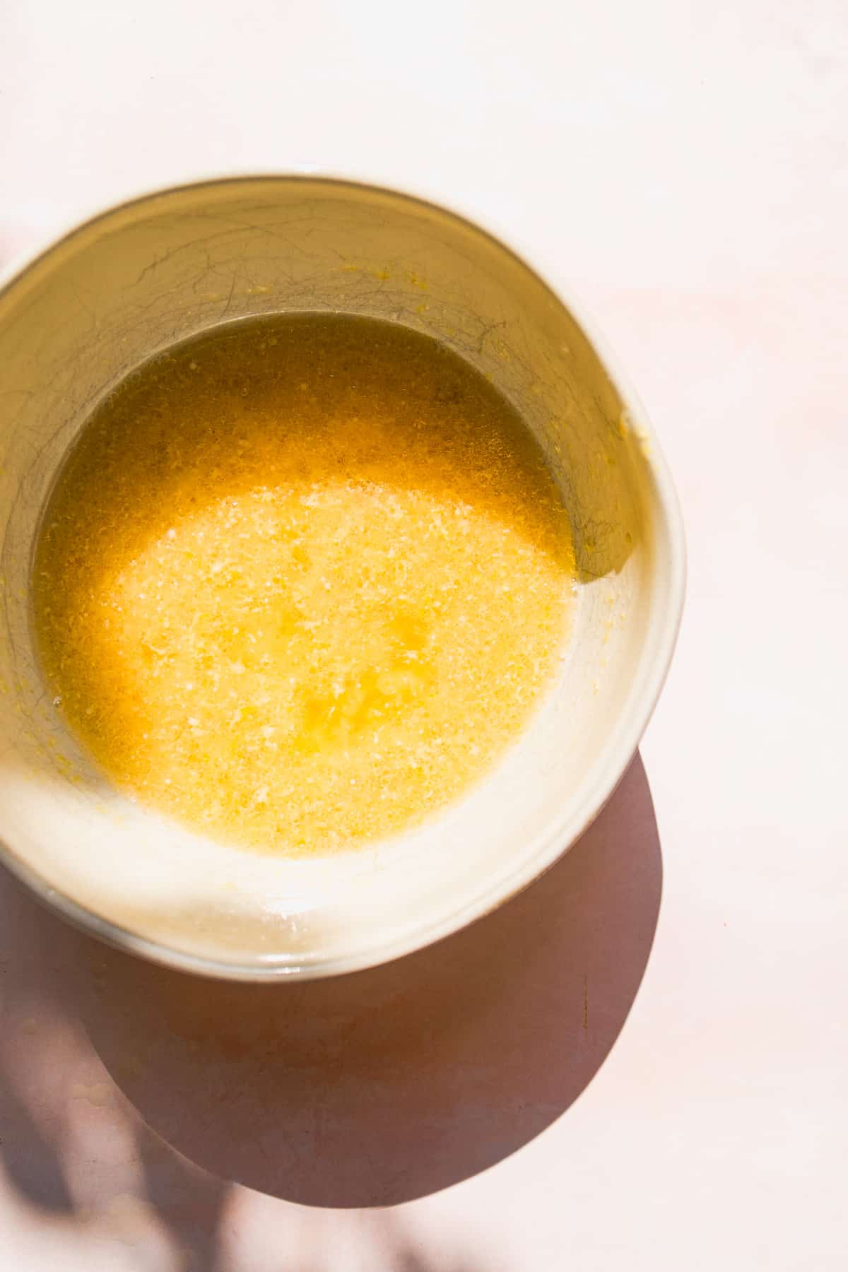 Overhead view of a bowl of lemon cake batter being whisked.