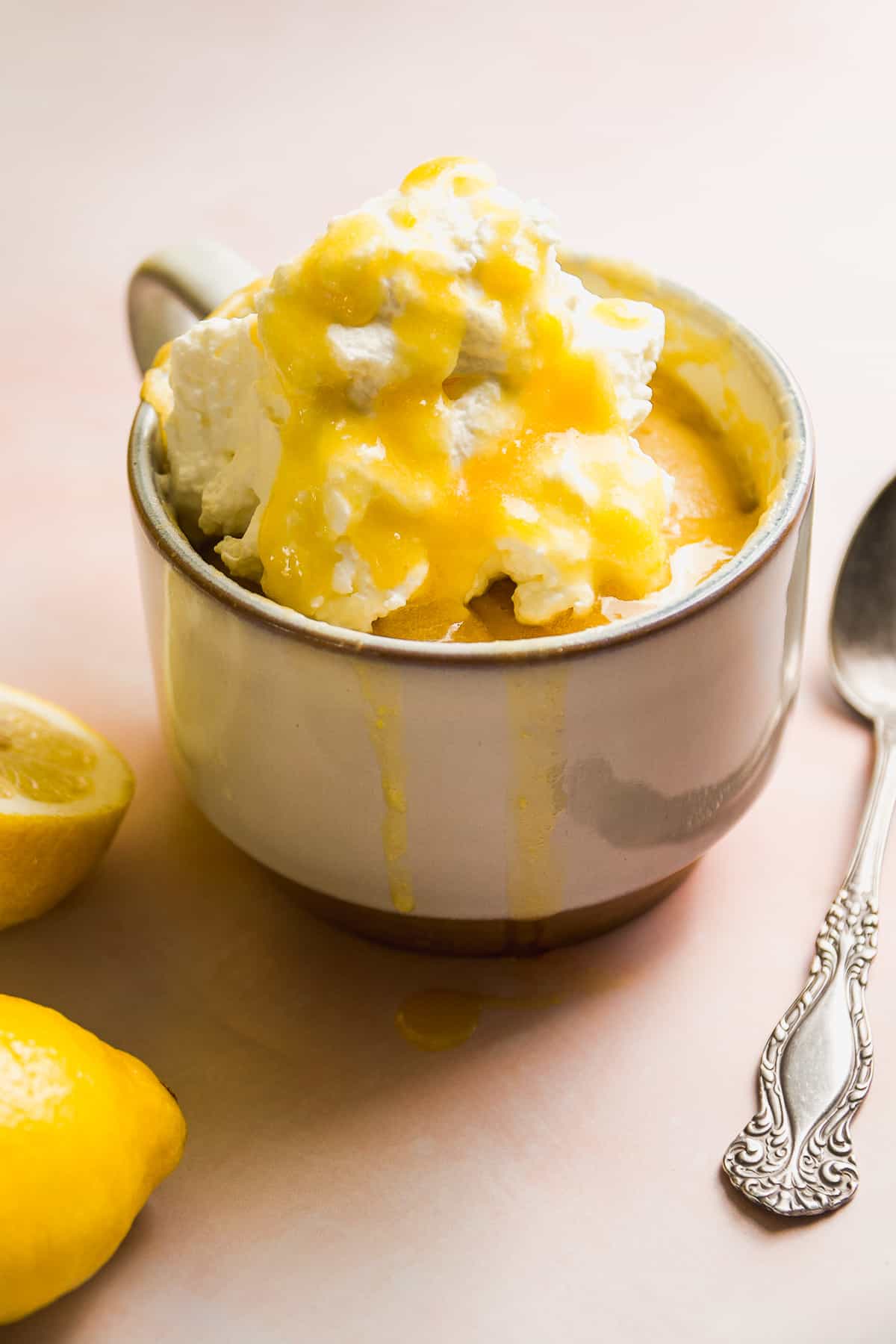 A coffee mug with lemon cake baked inside and whipped cream on top.