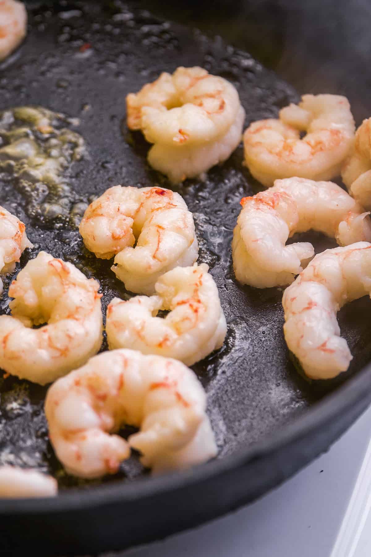 Shrimp being cooked in a black cast iron pan.