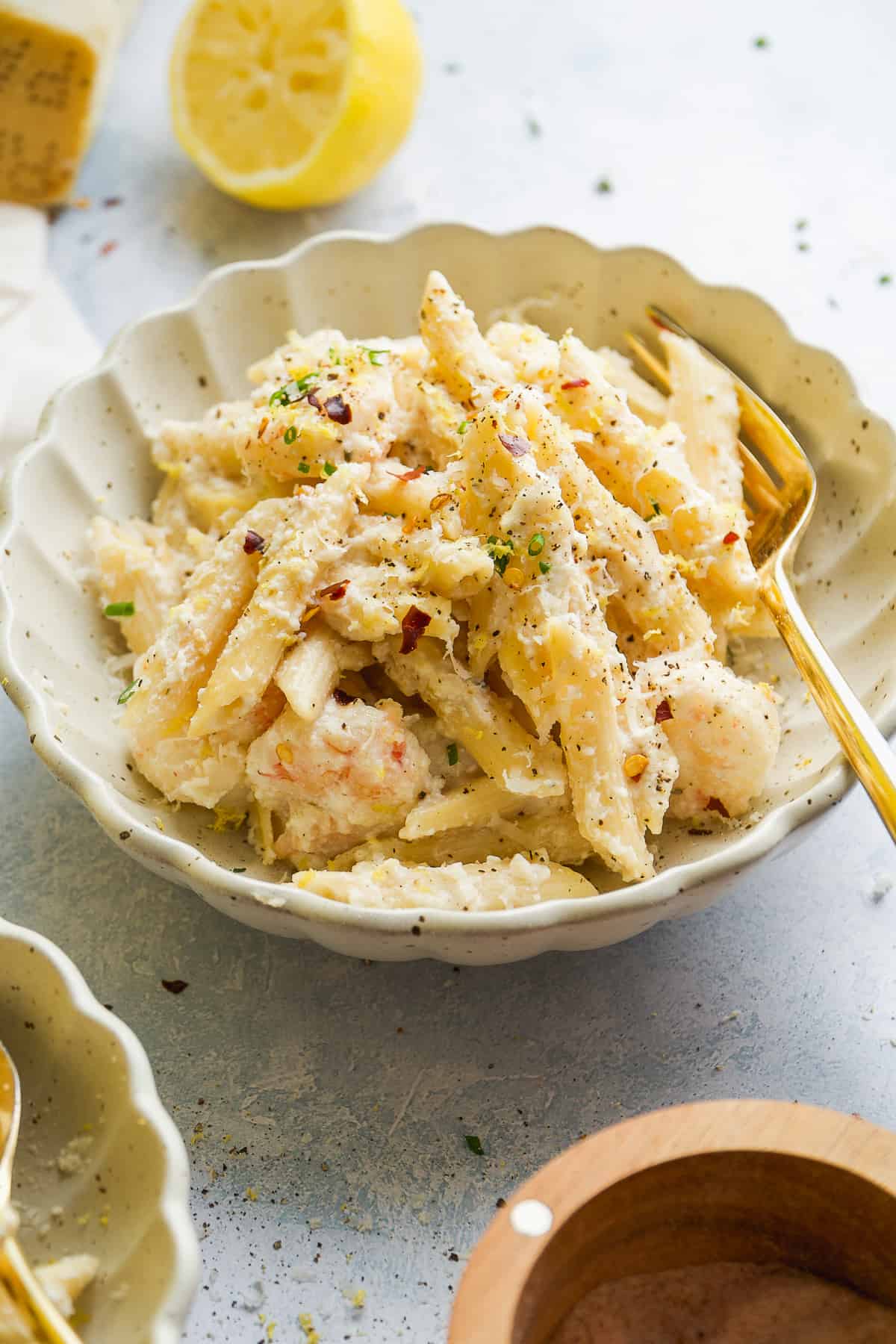 Bowl of lemon ricotta pasta with spices on top and gold fork resting inside.