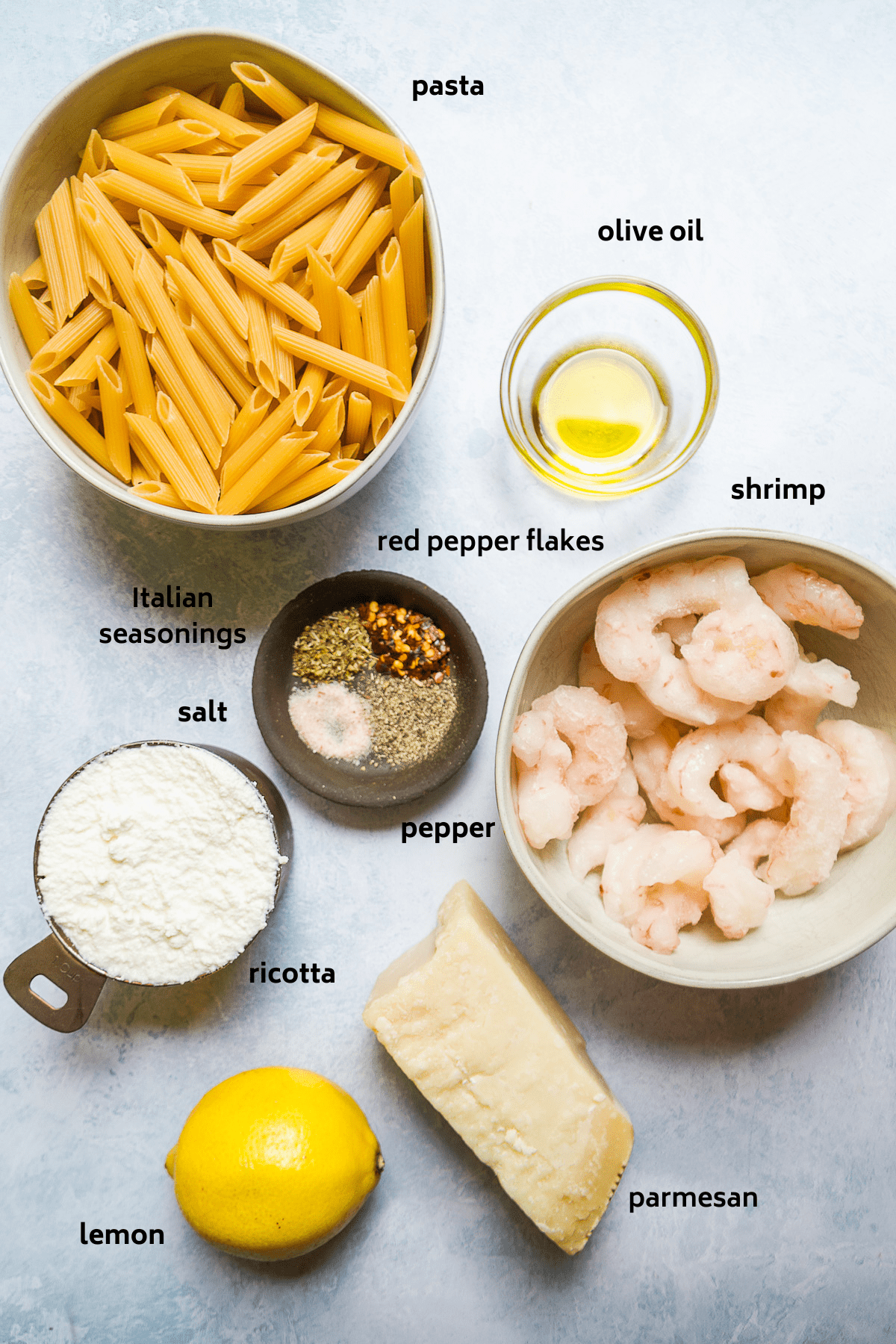 Lemon ricotta pasta ingredients on a blue surface with labels in black.