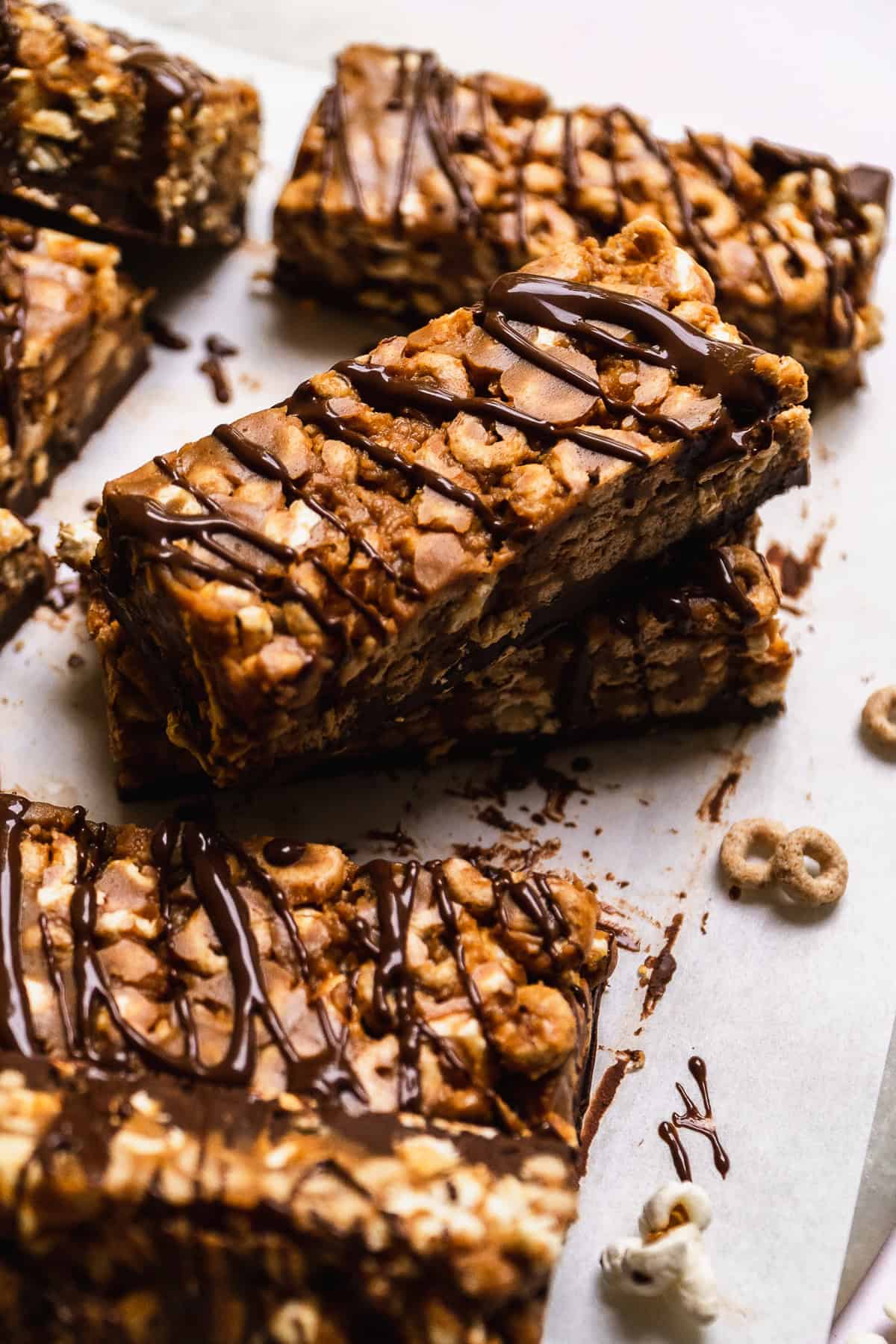 Chocolate peanut butter cheerio bars stacked on a piece of parchment paper.