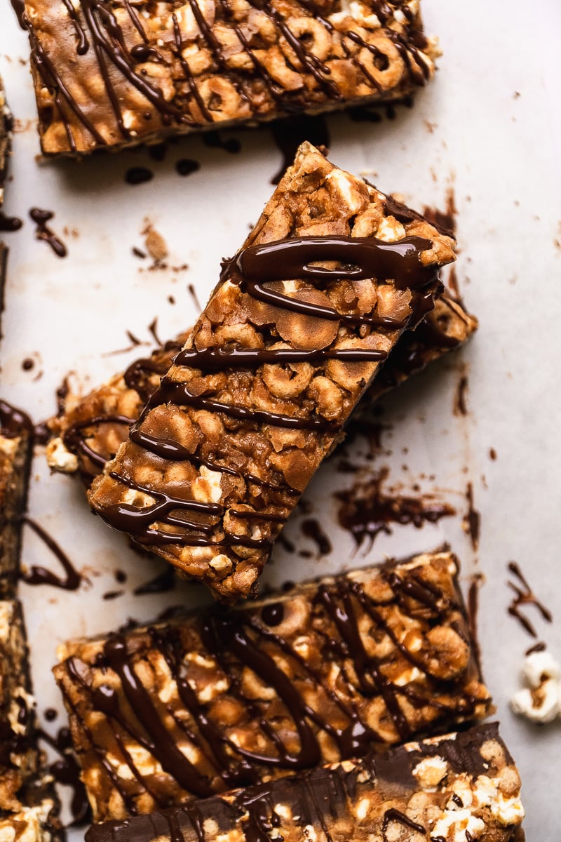 Peanut butter cheerio bars drizzled with chocolate and stacked on parchment paper