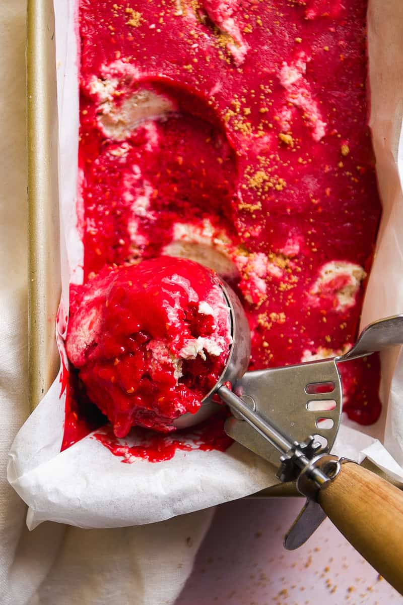 Raspberry sherbet with cheesecake pieces in a container.