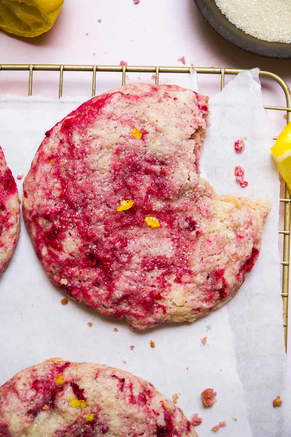 Raspberry lemonade cookie with a bite taken out of it on a wire rack.