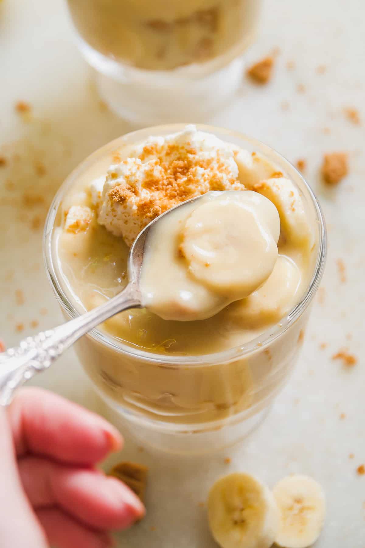 Person lifting a spoonful of dairy free banana pudding out of a glass.