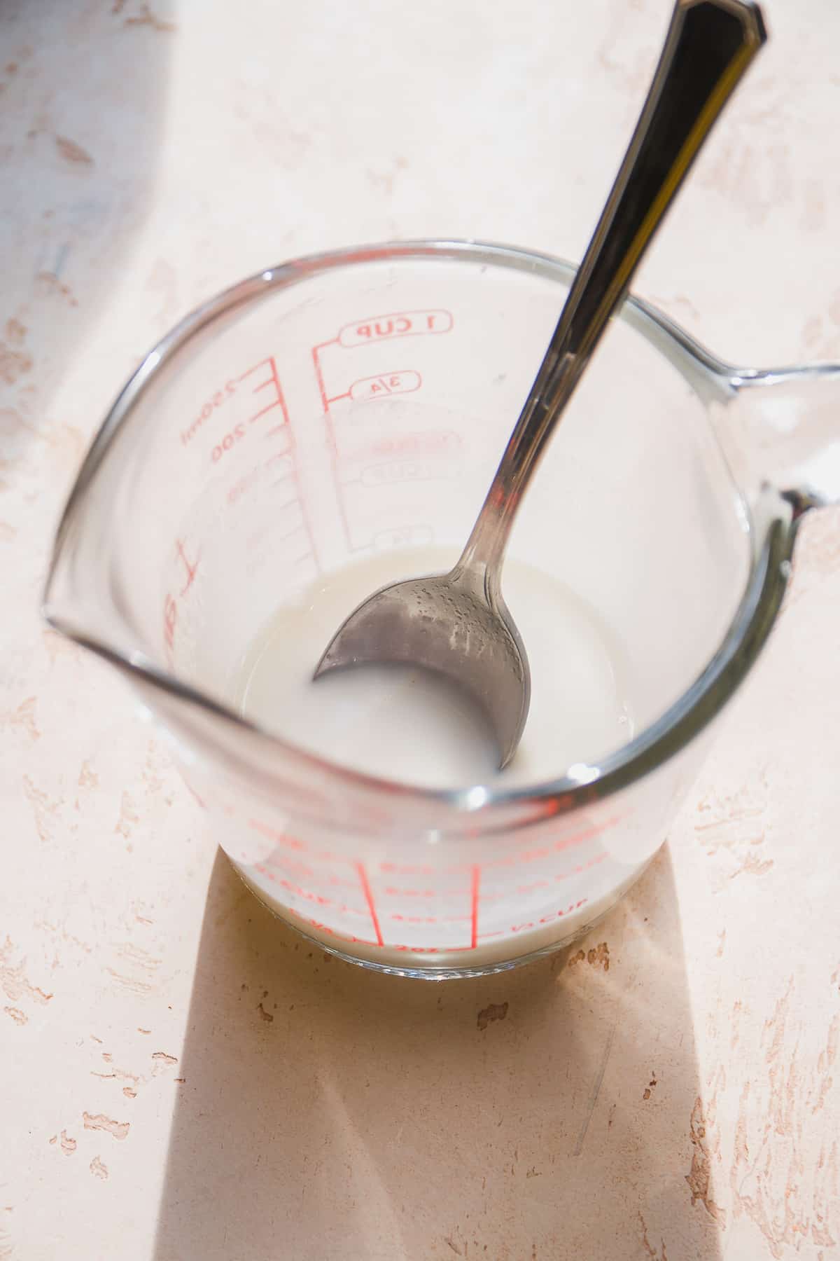 Measuring cup with a silver spoon inside.