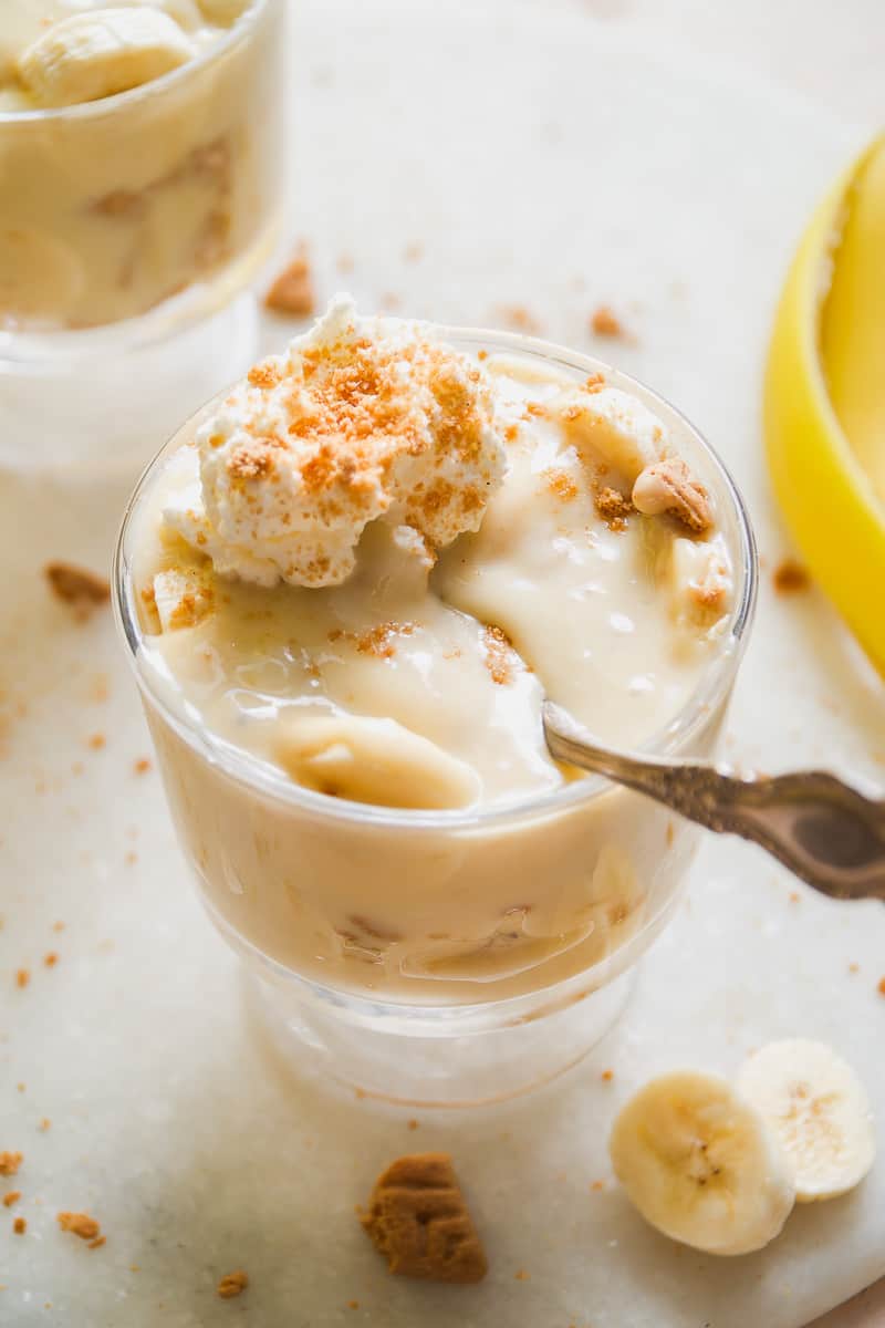 Small glass with dairy free banana pudding and a spoon resting inside.