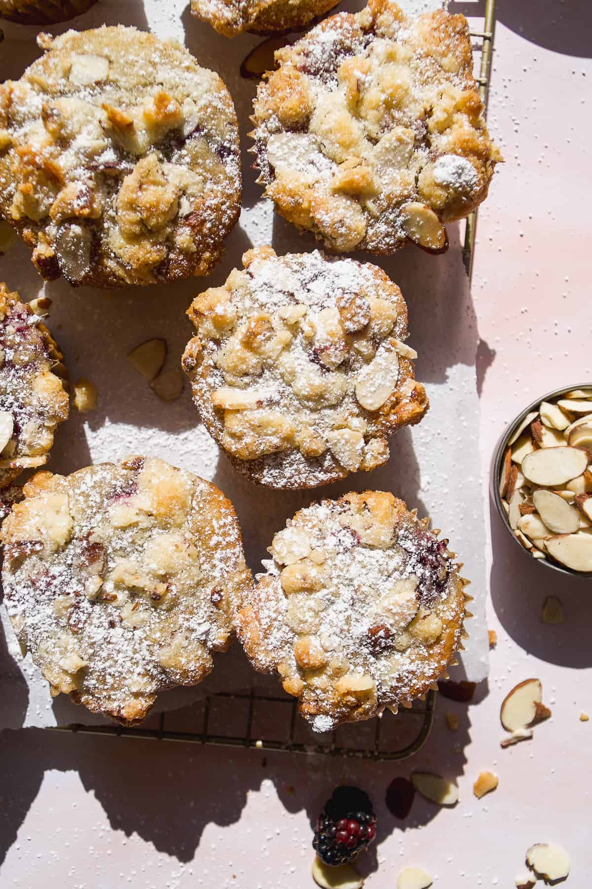 Gluten free almond flour blackberry muffins on a wire rack with powdered sugar.