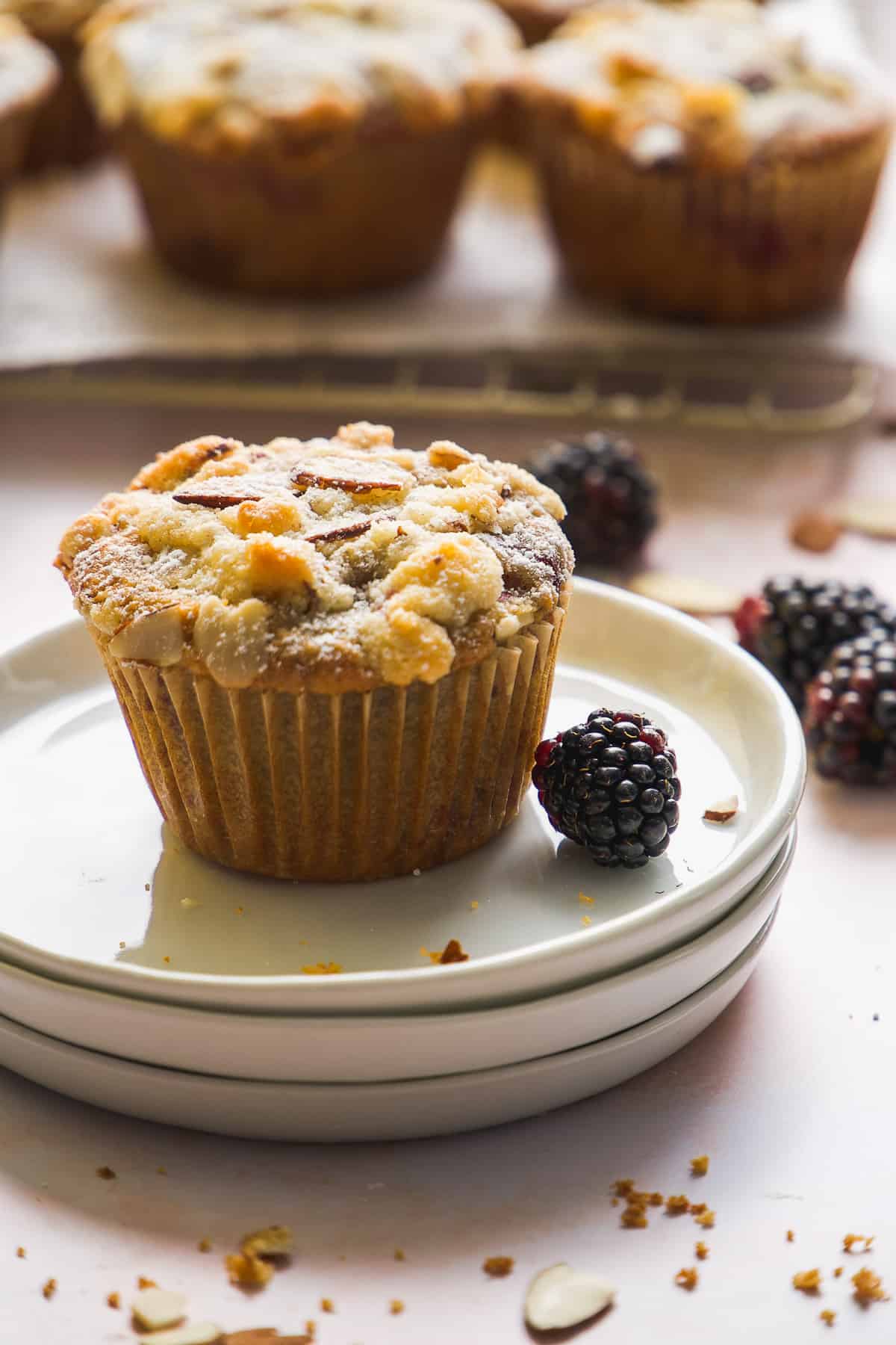 Blackberry muffin made with almond flour on a stack of small plates.