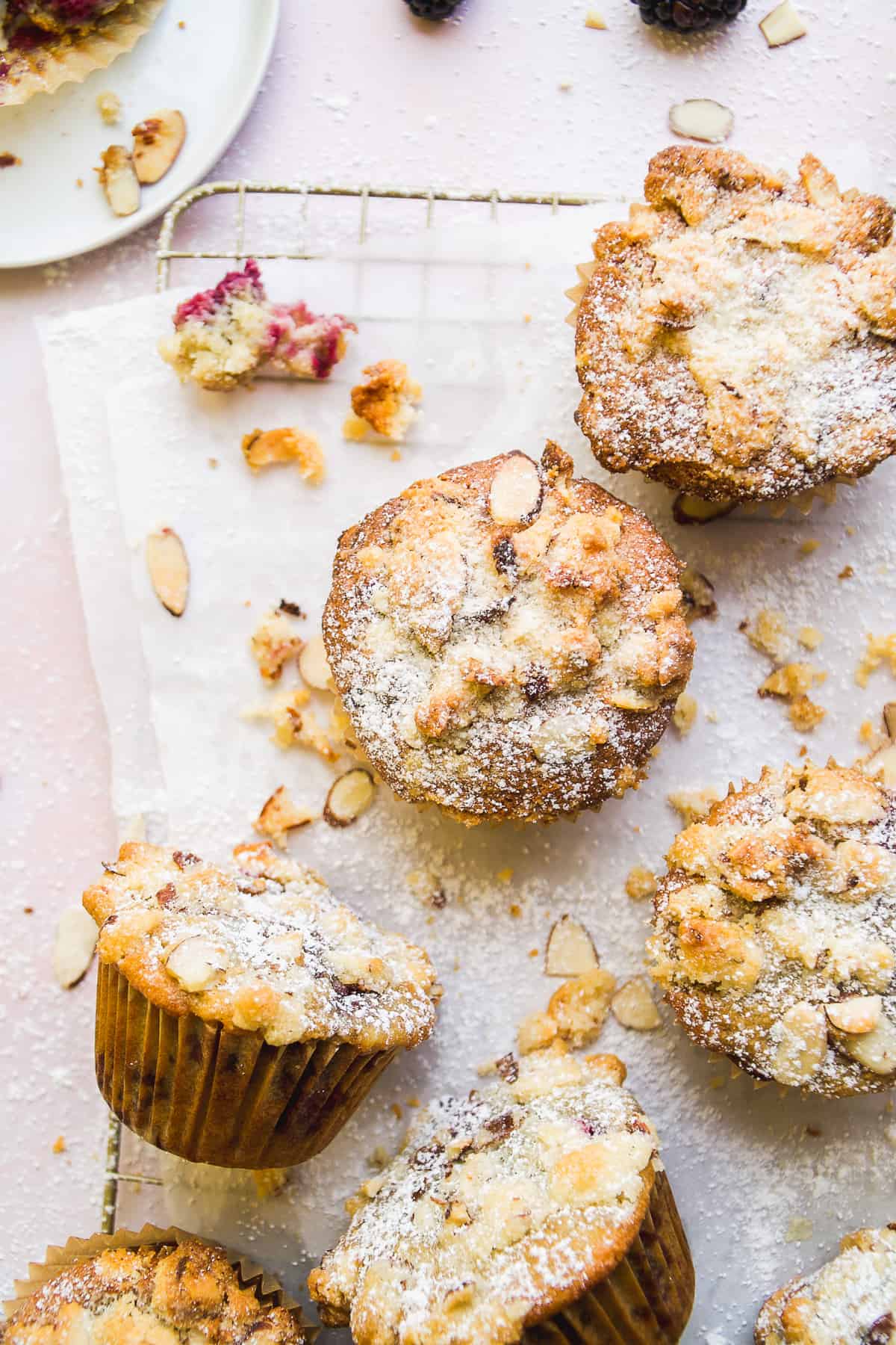 Gluten free blackberry muffins with almond topping on parchment paper.