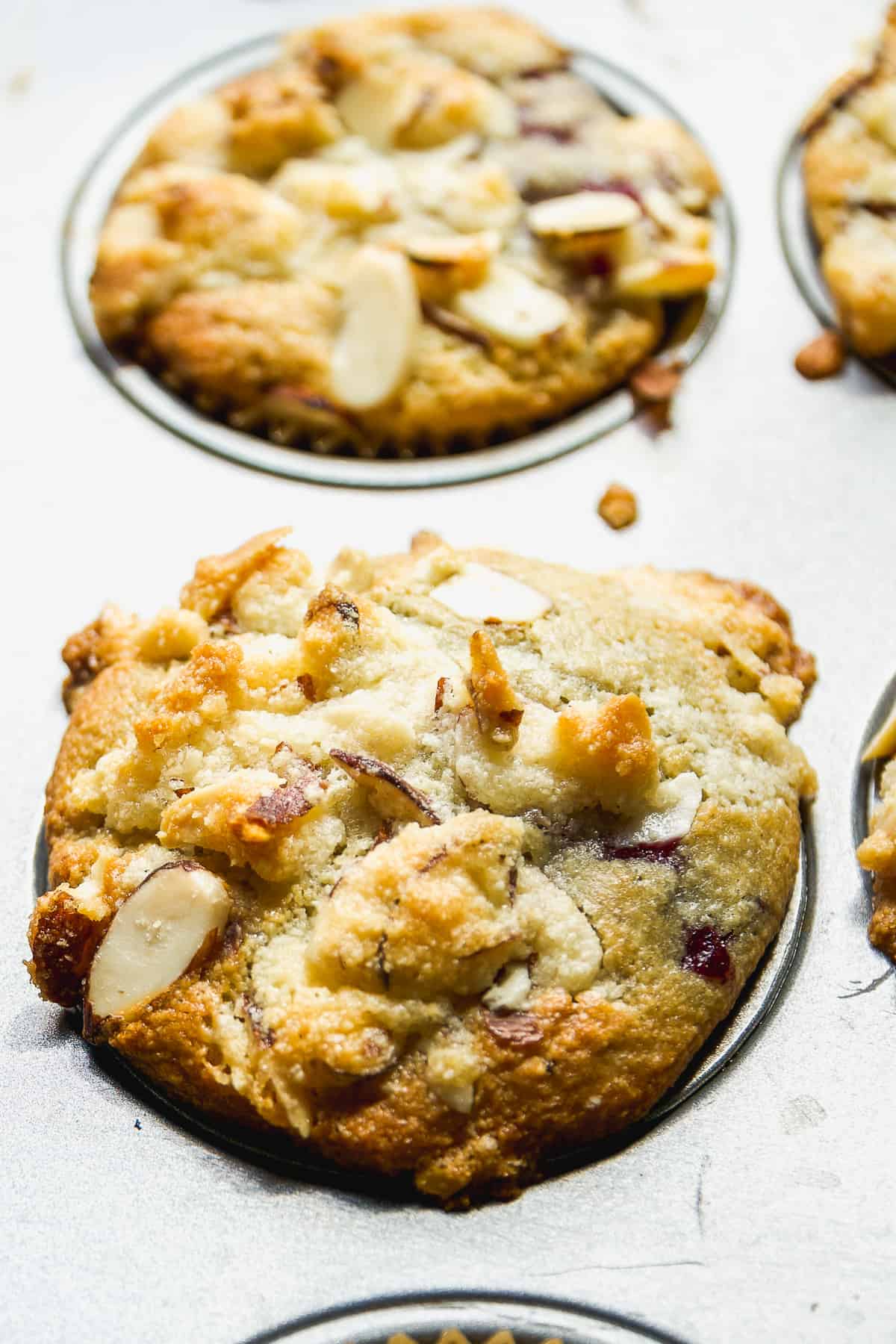 Almond flour blackberry muffin with almonds on top baked in a muffin tin.