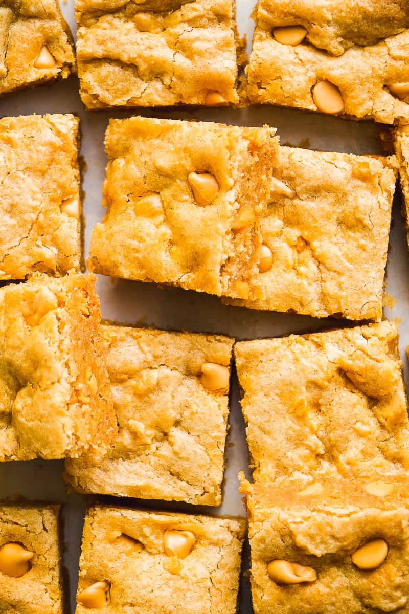 Squares of butterscotch blondies scattered on parchment paper.