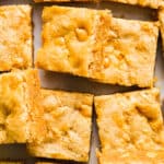 Butterscotch blondies cut into squares and scattered on parchment paper.