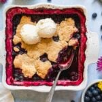 Gluten free blueberry cobbler in a baking dish with two scoops of ice cream.
