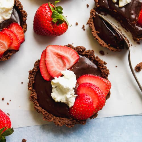 Mini chocolate tarts with strawberries on top.