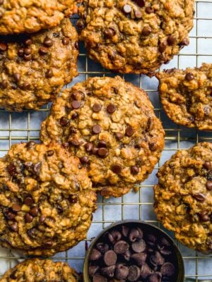 Peanut butter banana oatmeal cookies scattered on a wire rack with chocolate chips.