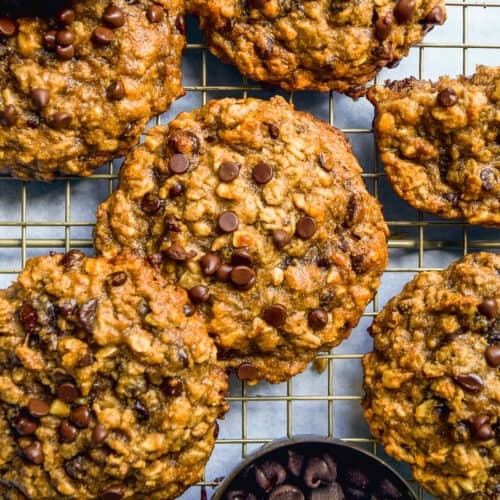 Peanut butter banana oatmeal cookies scattered on a wire rack with chocolate chips.