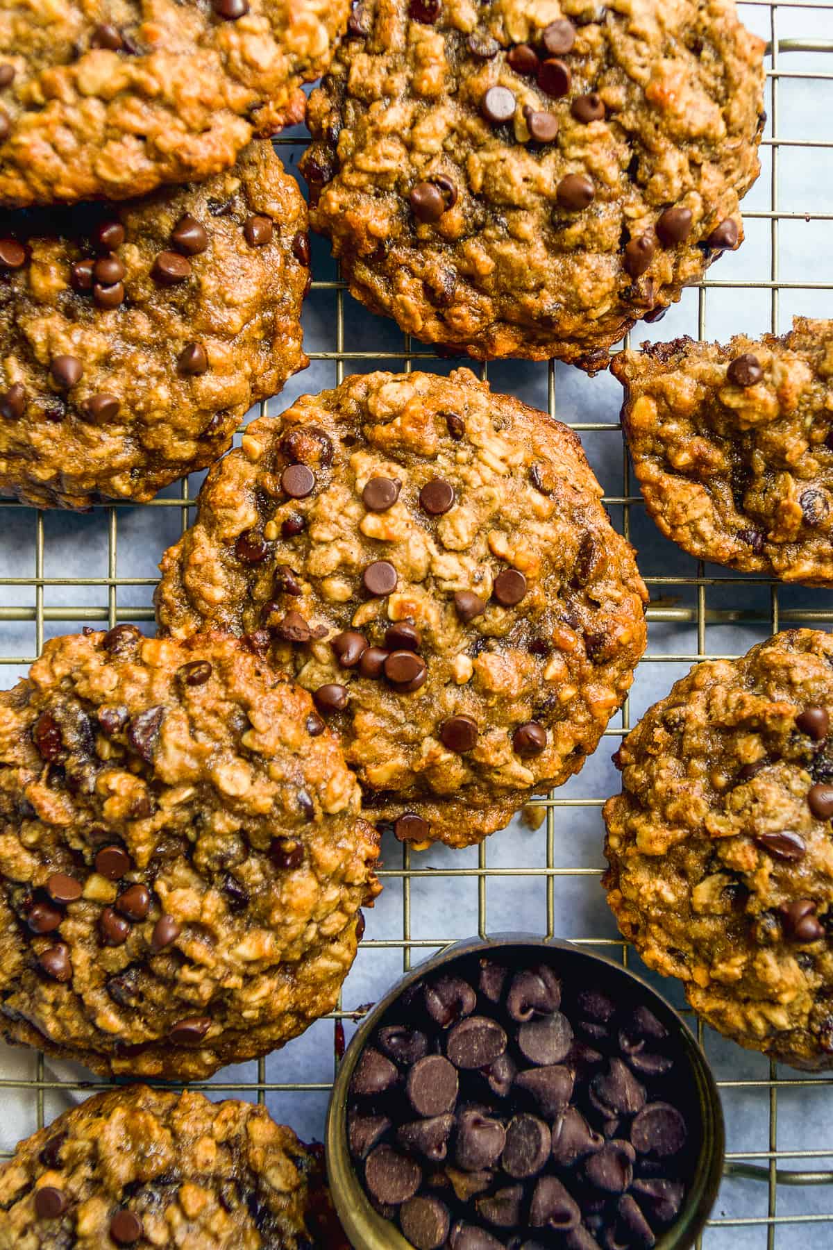 Peanut butter banana oatmeal cookies scattered on a wire rack with chocolate chips.