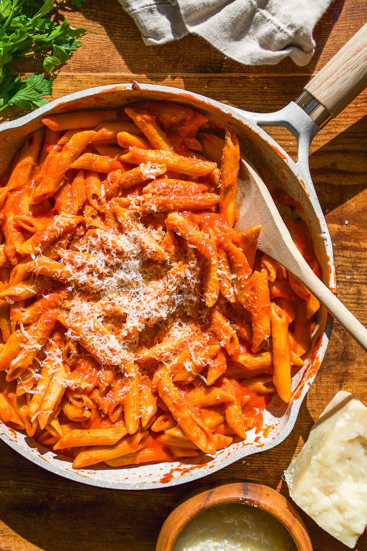 Skillet with spicy vodka pasta and a wooden spoon resting inside.