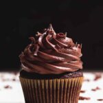 Gluten free chocolate cupcake in front of a black backdrop.