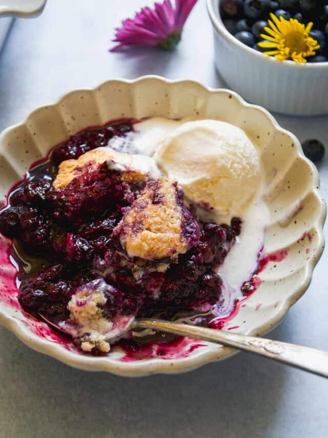 A bowl of blueberry cobbler with a scoop of ice cream on top.