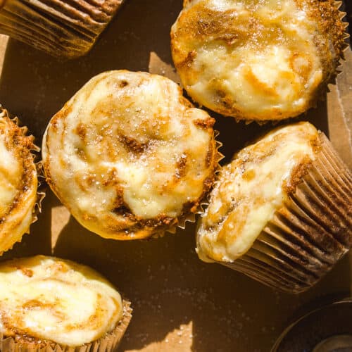 Almond flour pumpkin muffins with cream cheese swirl scattered on parchment paper.