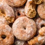 Gluten free apple cider doughnuts scattered on a pan.