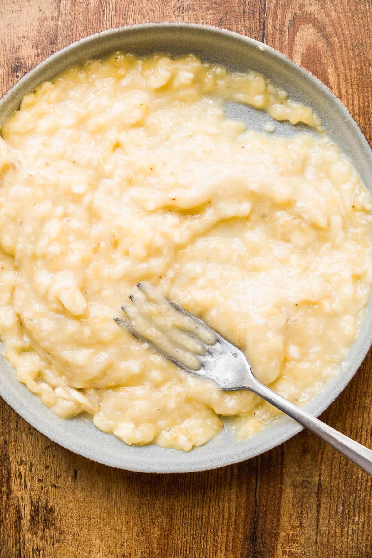 Mashed bananas on a plate with a fork.