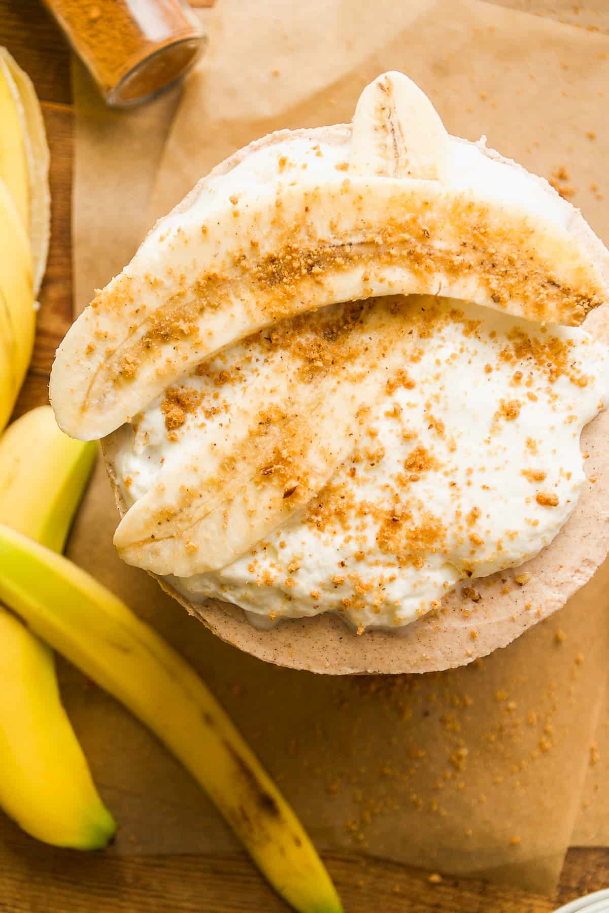 Overhead view of a gluten free banana cake with whipped cream and banana slice.