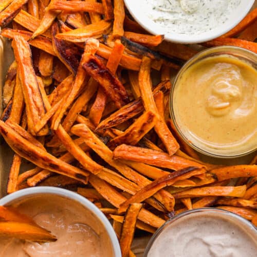 Sweet potato fries with dipping sauces on a baking pan.