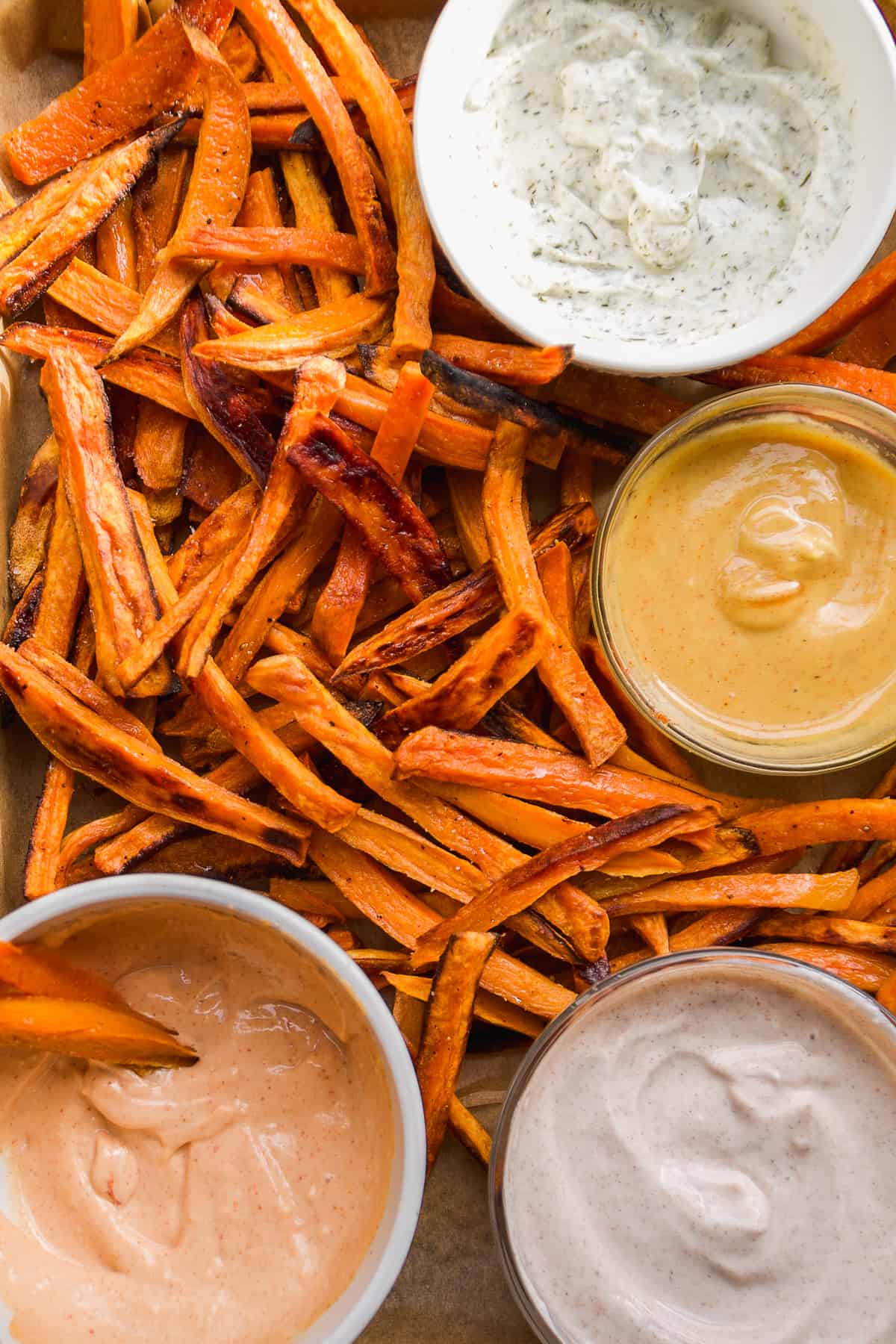 Sweet potato fries with dipping sauces on a baking pan.