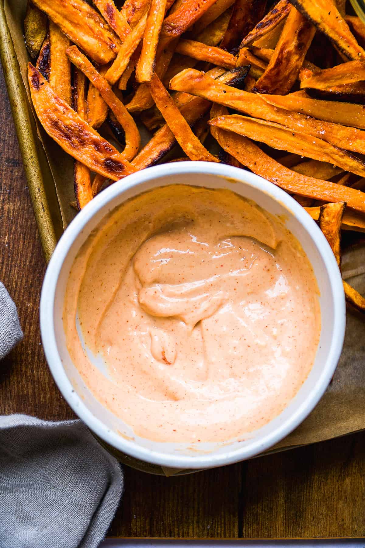 Chipotle aioli sauce on a pan with sweet potato fries.