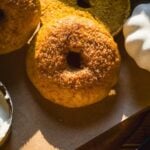 Pumpkin bagels with cinnamon sugar on top on parchment paper.