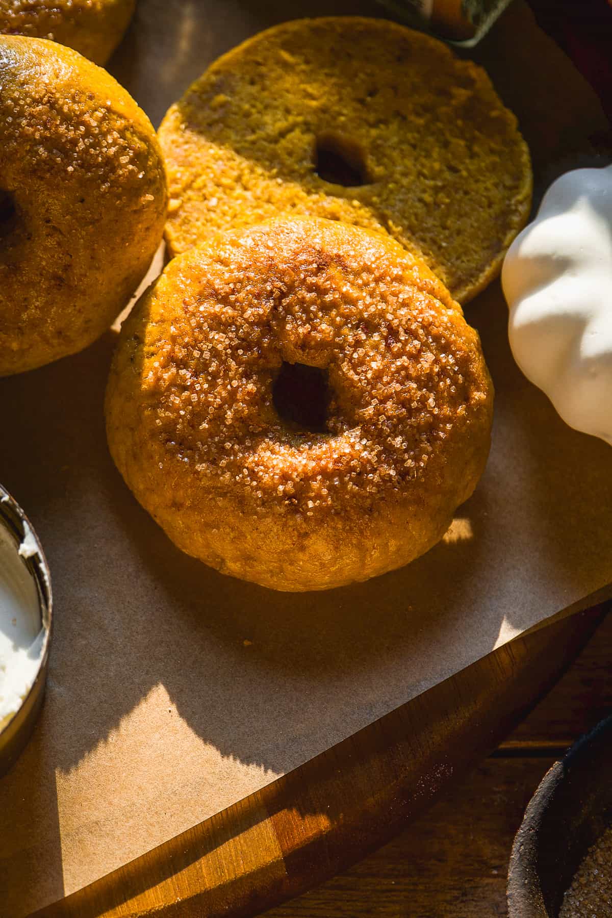 Pumpkin bagels with cinnamon sugar on top on parchment paper.